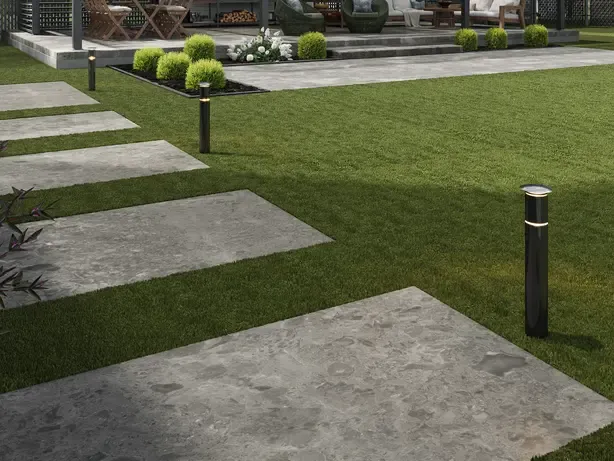 Terrasse extérieure avec pavés de pierre et bandes de gazon synthétique.